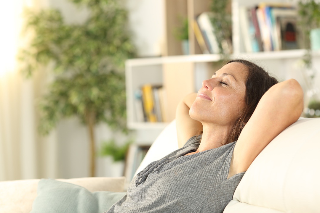 Woman relaxing in cool California home after using AC maintenance best practices