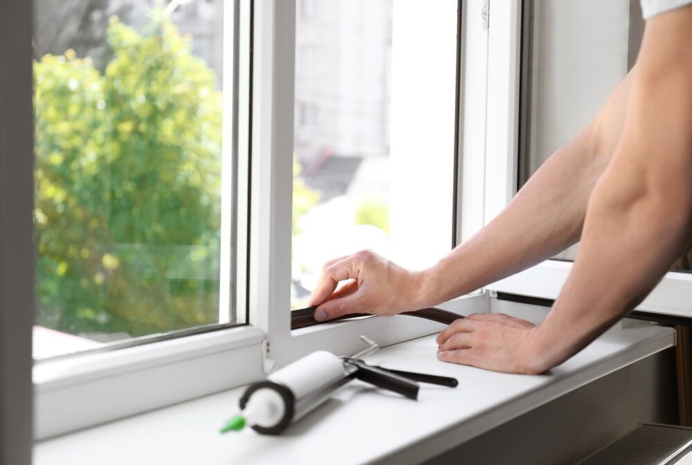 California homeowner sealing windows to improve AC efficiency