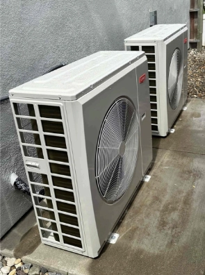Two outdoor air conditioning condenser units are installed on a concrete pad next to a gray building wall, with convenient financing options available for easy upgrades.